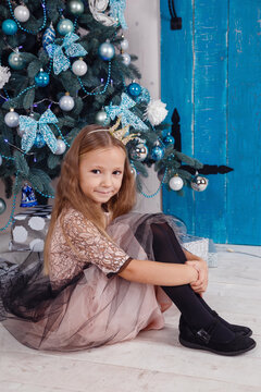 Cheerful cute little child girl with present near Christmas tree indoors.