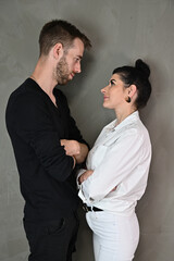 Stylish vertical studio portrait of a caucasian brunette woman and man in a love relationship on a gray background