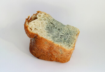 Half a loaf of white bread with blue and green mold on a white background. Selective focus. Moldy, spoiled bread.