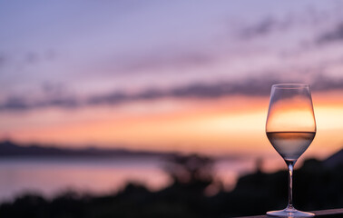 A Glass of white wine with a beautiful sunset in the background