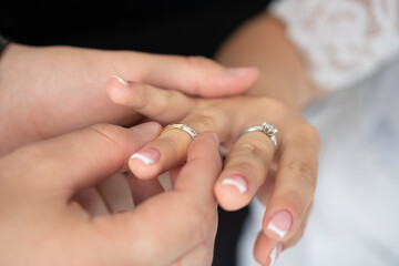 The groom puts the wedding ring on the finger of his bride. Selective focus. Wedding concept, traditions.