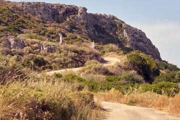 A winding road in mountains of Crete Greece with roof of road church and rocks on the background.