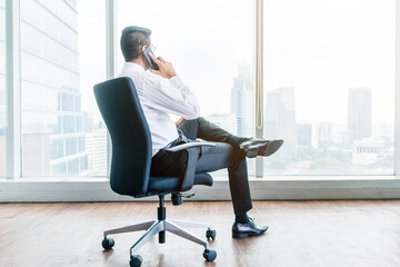 Rear view of businessman talking on phone while sitting down
