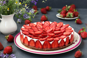 Homemade strawberry cheesecake, decorated with fresh strawberries, on a plate on a dark background, close-up, horizontal format