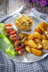 Shish kebab served with roasted potatoes and salad.