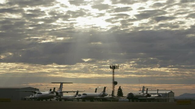 Parked airplanes on tarmac of runway at airport under surreal heaven sunbeams. Grounded Planes In Great Falls Airport.