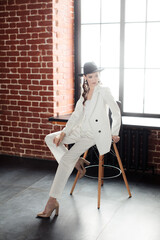 Young girl in a white suit and a black hat. The concept of clothing.