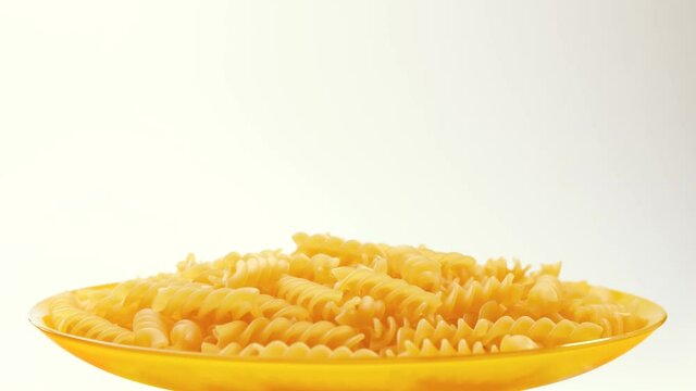 Plate of raw italian fusilli pasta on white background with copy space, 4K UHD video footage
