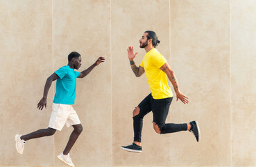 Full length portrait of a two excited young men pointing arms away while jumping isolated over wall  background. Image of two joyful men while jumping and gesturing together. Image