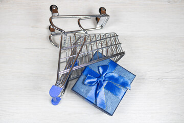 Shopping cart with scattered gifts on a light background.