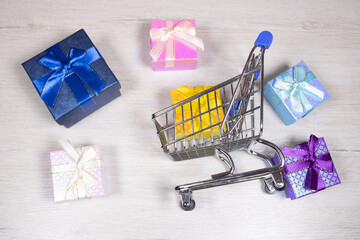 Shopping cart with scattered gifts on a light background.