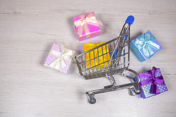 Shopping cart with scattered gifts on a light background.