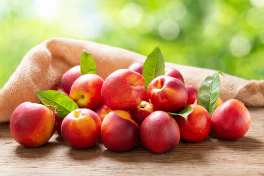 fresh ripe nectarines with leaves on a wooden table