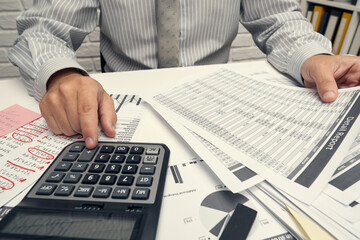 Business analysis and accounting concept - businessman working with document, spreadsheet, using calculator, tablet pc. Office desk closeup.