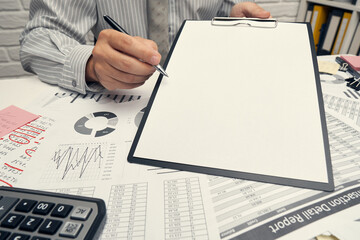 Business analysis and accounting concept - businessman working with document, spreadsheet, using calculator, tablet pc. Office desk closeup.