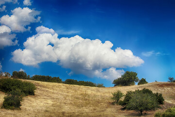 Beautiful cloud between two hills, scorched grass. Summer