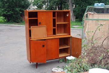 old wooden secretaire with drawers and open doors thrown into the trash
