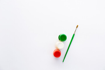 Three different colors white, red, green and brush for painting. Tools for painting or decorating in the New Year's palette. Jars with acrylic or gouache.