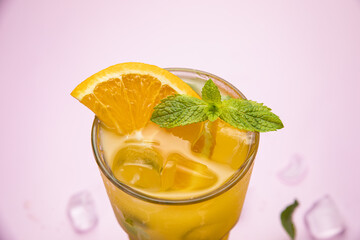 smoothie with orange on a pink table. Decorated with mint, ice. Healthy food for breakfast and snack
