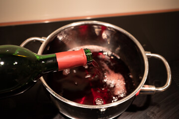 a mulled wine is poured into a saucepan to heat it up