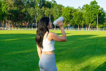 fit girl drinking water at stadium. beautiful sportive woman at football field