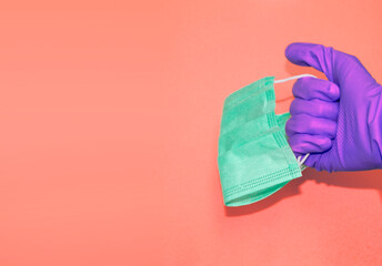 Hand in protective glove holds face mask. Stuff for health care and infection prevention. Banner template with copy space.