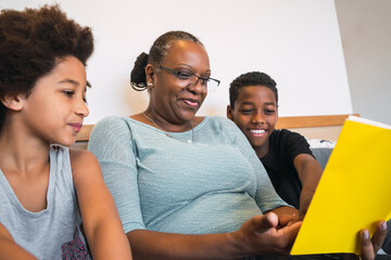 Grandmother reading a book to grandchildren.