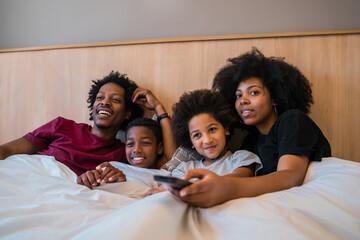 Family watching a movie on bed at home.