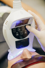 Teeth whitening using an ultraviolet lamp. Dentist doing teeth whitening procedure with ultraviolet...