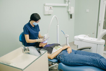 Obraz premium Dentist stomatologist whitening teeth for patient in medicine dental clinic with lamp. Concept of teeth care and dentistry. Teeth whitening procedure