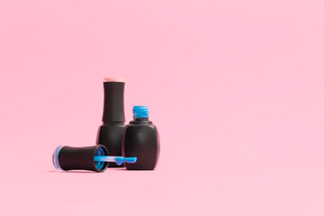 Bottles of nail polish on light pink background, selective focus, copy space