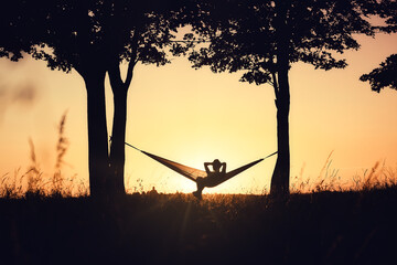 People on vacation. A girl's silhouette in a hammock between trees. A hammock in the background of...