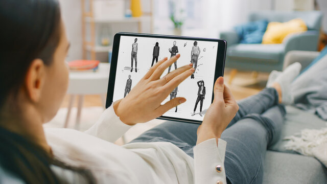 Young Woman Artist at Home Using Tablet Computer in Horizontal Landscape Mode Drawing and Choosing the Best Sketch of a Person She Made. Woman Using Gestures with Touchscreen Device.