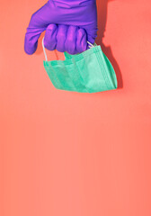 Hand in protective glove holds face mask. Stuff for health care and infection prevention. Banner template with copy space.