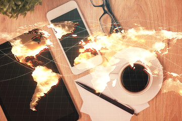 Double exposure of business theme hologram over desktop with phone. Top view. Mobile international...
