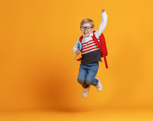 Happy school boy jumping with raised arm.
