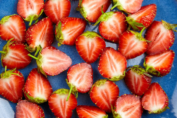 Fresh strawberry cut in half on blue plate background.