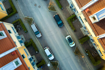 Aerial view of residential houses with red roofs and streets with parked cars in rural town area. Quiet suburbs of a modern european city.