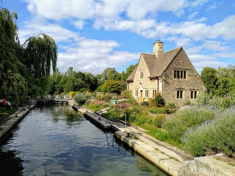 A house by a canal lock in Oxfordshire in the summer with a blue sky.
