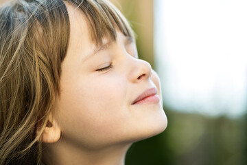 Portrait of young pretty child girl with long hair enjoying warm sunny day in summer outdoors. Cute...