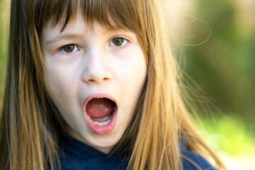 Portrait of surprised child girl outdoors in summer. Shocked female kid on a warm day outside.