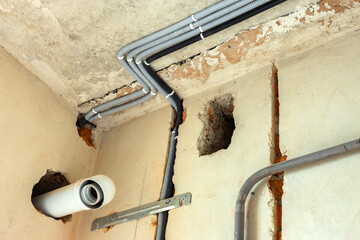 Electrical cables laid in protective corrugation installed on the ceiling and wall in a room under...