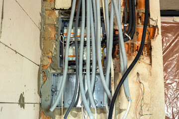 Electrical cables laid in protective corrugation installed on the ceiling and wall in a room under construction works.
