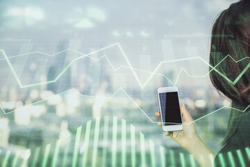 Double exposure of forex chart sketch hologram and woman holding and using a mobile device. Stock...