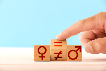 gender equality concept. a man flips a wooden block and changes the equal sign to an inequality between the man and woman icons