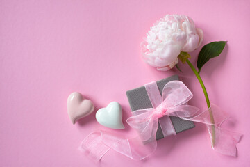Pink background with peony, hearts and box with a gift, space for text, congratulations