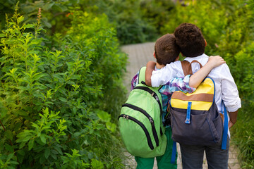 European boy and African American stand with backpacks back