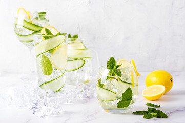 Alcohol drink (gin tonic cocktail) in a variety of glasses with lemon, cucumber, mint leaves and ice. Iced drink with lemon.