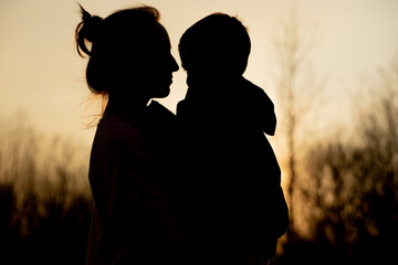 Silhouette of a mother and son playing outdoors at sunset. Mother's day concept
