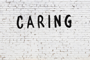 Inscription caring painted on white brick wall